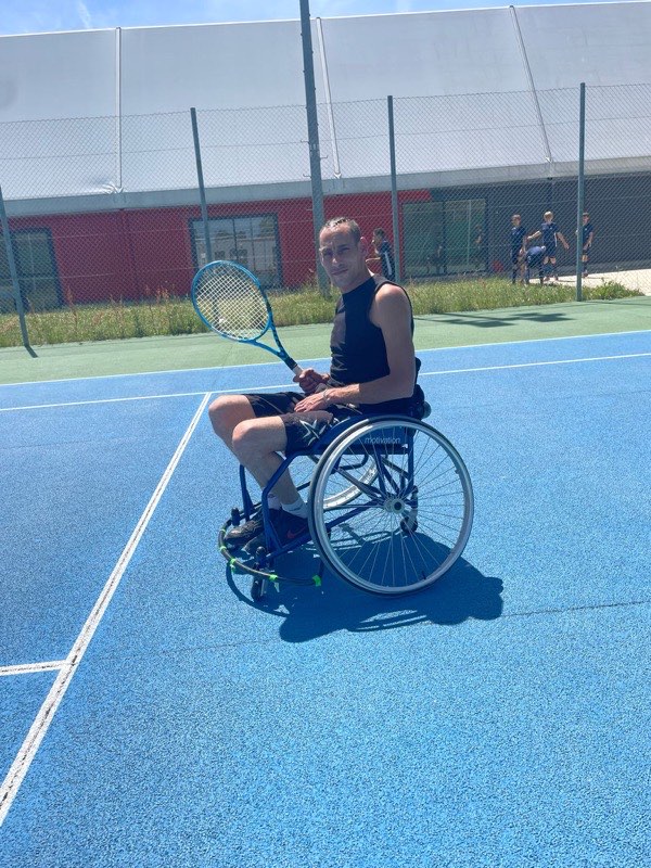 Axel Broutin en fauteuil de tennis sur un court, raquette en main